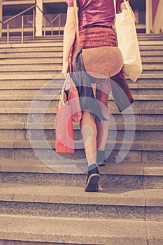 Young woman with shopping walking up stairs