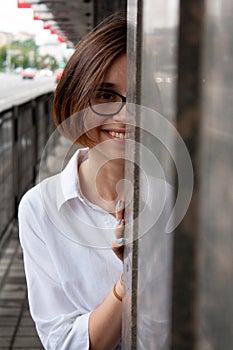 A young woman with short brown hair, wearing a white shirt, with glasses