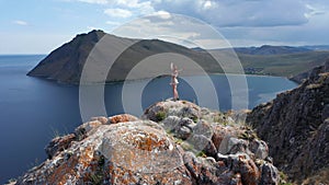 Young woman in short dress running up on top of mountain above the sea