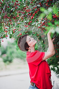 Young woman with short hair-cut standing near cherry tree