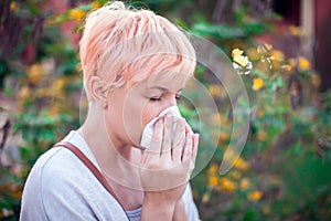 Young woman with short hair sneezing into tissue. flu, allergy, runny nose. Healthcare concept