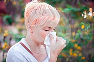 Young woman with short hair sneezing into tissue. flu, allergy, runny nose. Healthcare concept