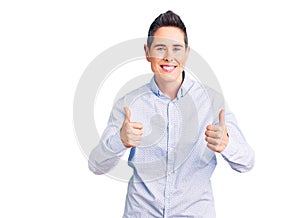 Young woman with short hair wearing business clothes success sign doing positive gesture with hand, thumbs up smiling and happy