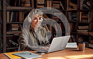 Distancia educación. mujer joven corto cabello en auriculares sobre el escritorio el estudio conectado a internet sobre el computadora portátil escuchando una lectura 