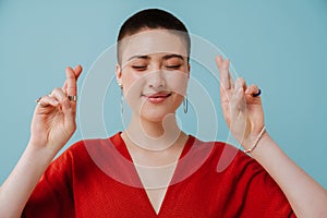 Young woman with short haircut holding fingers crossed for best luck