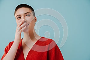 Young woman with short haircut smiling and covering her mouth