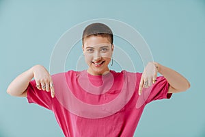 Young woman with short haircut smiling and pointing fingers downward