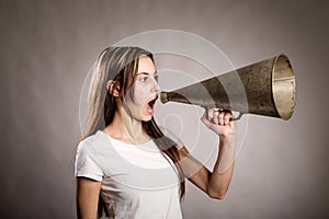 Young woman shouting with an old megaphone