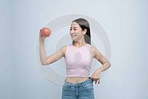 young woman show loose pants on waist after weightloss hold red apple isolated on white background