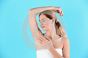 Young woman showing armpit on color background