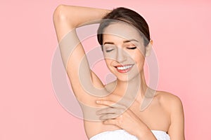 Young woman showing armpit with smooth clean skin on background