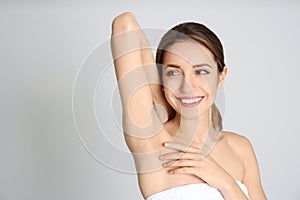 Young woman showing armpit with smooth clean skin on grey background