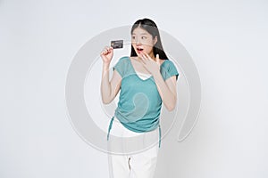 Young woman showing credit card with mouth open and looking at camera with excited and surprised stand over white background