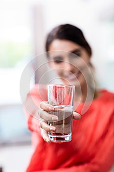 Young woman showing drinking glass with water