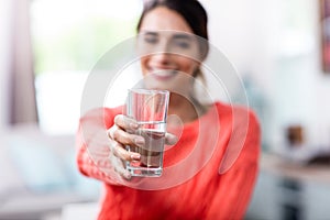 Young woman showing drinking glass with water photo