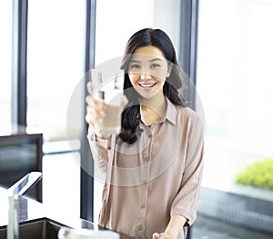Young woman showing drinking glass with water in kitchen