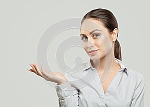 Young woman showing empty copy space on the open hand on white background. Product placement and advertising marketing concept