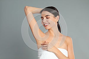 Young woman showing hairless armpit after epilation procedure on background