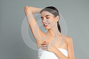 Young woman showing hairless armpit after epilation procedure on background photo