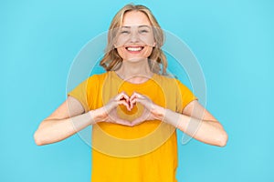 Young woman showing heart shape with fingers, feeling love