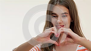 Young woman showing heart shape gesture