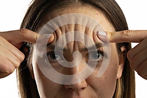 Young woman showing her forehead wrinkles with her fingers