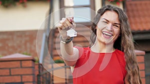 Young Woman Showing the Key from her New House in the Suburbs. Attractive Girl Holding Keys While Standing Outdoor