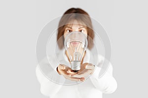 young woman showing light bulb in open hands presenting giving gesture concept energy saving and idea on infinite background 3D