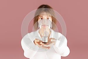 young woman showing light bulb in open hands presenting giving gesture concept energy saving and idea on infinite background 3D