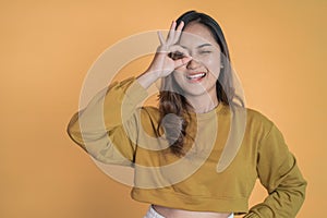 Young woman showing oke gesture with eye looks imitating binoculars