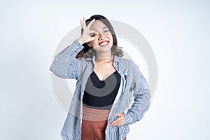 Young woman showing oke gesture with eye looks imitating binoculars