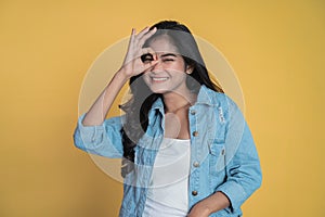 Young woman showing oke gesture with eye looks imitating binoculars