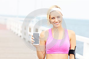 Young woman showing phone over pier