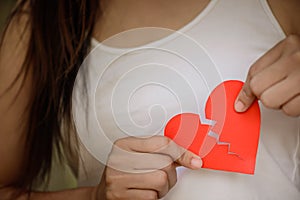 Young woman showing red ripped paper heart.