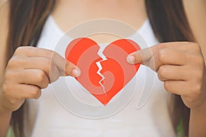 Young woman showing red ripped paper heart.