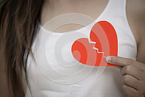 Young woman showing red ripped paper heart.