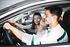 Young woman showing a road in front of the car while the driver using a mobile phone and losing concentration. Dangerous driving.