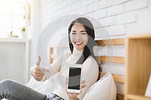 Young woman showing smart phone empty screen to camera