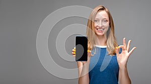 Young woman Showing Smartphone Blank Screen and showing OK gesture