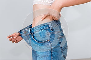 Young woman showing successful weight loss with her jeans., Heal