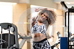 Young Woman Showing Thumbs Up While Standing Strong In The Gym And Flexing Muscles