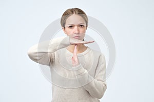 Young woman showing time out gesture with hands isolated on gray wall background. Negative human emotion
