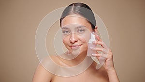 Young woman shows off a bottle with a foam dispenser for washing