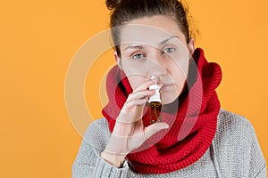 A young woman of a sickly look sprays a cure for colds and flu in her nose