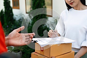 Young woman signature in document to receive package from professional delivery man at home