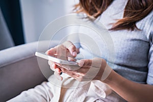 Young woman siiting on sofa and using smart phone
