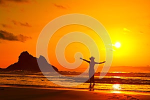 Young woman silhouette on the beach in summer sunset lght