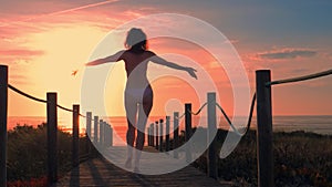 Young woman silhouette in a wooden foot bridge at the beach at sunset