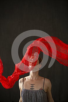 Young woman in silver dress with red scarf floating above.