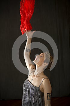 Young woman in silver dress with red scarf floating above.